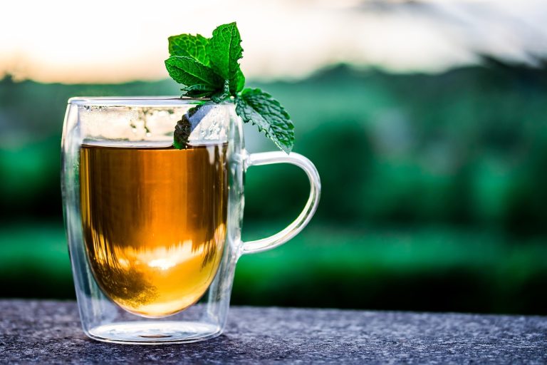 Tata Consumer Q2 results: a glass mug of tea topped with fresh mint leaves against a green garden background