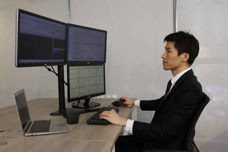 Three outside up pattern: a trader at a multi-monitor desk studying price action