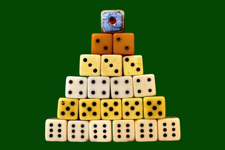 Trading expectancy concept: a pyramid of dice on a green table, a reminder that outcomes are probabilities