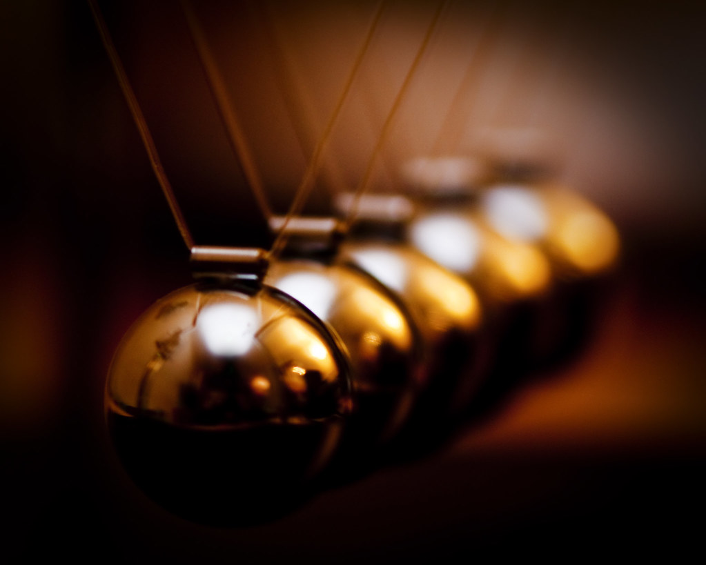 Ultimate oscillator momentum idea: close-up of polished golden steel balls on a Newton’s cradle