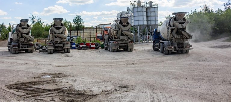 UltraTech Cement Q2 results: cement mixer trucks parked in front of grey storage silos at a cement yard
