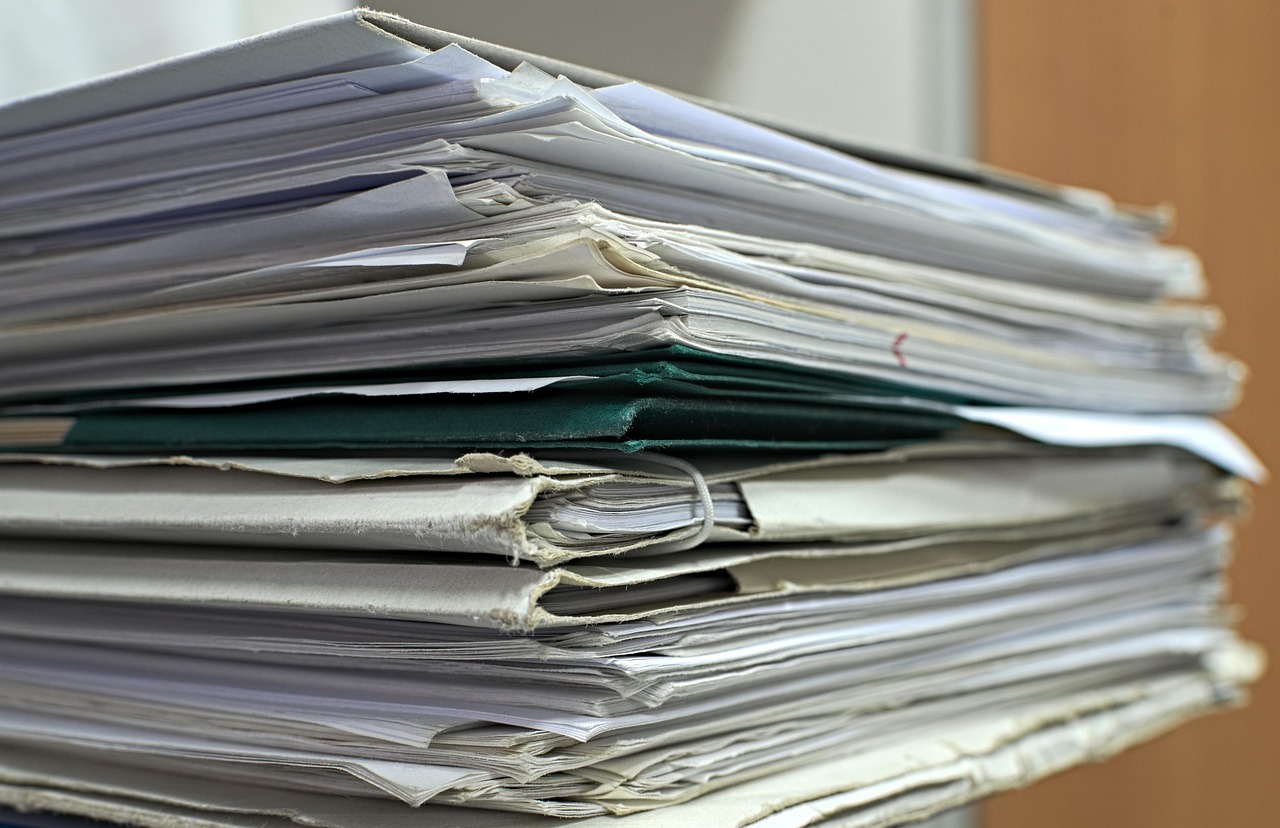 Unbilled revenue meaning: a tall stack of paper files and project folders waiting to be processed in an office