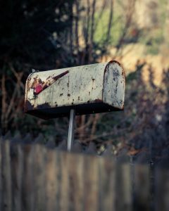 Unclaimed dividend: an old weathered mailbox left on its post