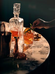 United Spirits Q2 results: crystal whisky decanter and a garnished drink on a marble bar table